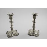 A PAIR OF MID 18TH CENTURY CAST CANDLESTICKS on shaped square bases with shell decoration, well