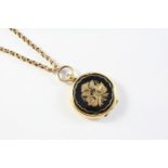A 9CT GOLD CHAIN suspending a circular gold locket pendant, with black enamel and gold foliate