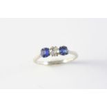 A SAPPHIRE AND DIAMOND THREE STONE RING the circular-cut diamond is set with two cushion-shaped