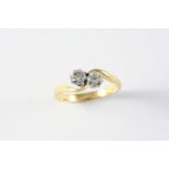 A DIAMOND CROSS-OVER RING set with two circular-cut diamonds, in 18ct gold. Size L