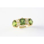 A PERIDOT AND DIAMOND RING the three oval-shaped peridots are set with four old cushion-shaped