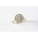 A DIAMOND CLUSTER RING the old cushion-shaped diamond is set within a surround of eight old