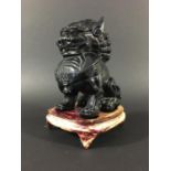 CHINESE GUARDIAN LION 20th century, probably amber, on a hardwood stand, height 19cm