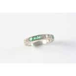 AN EMERALD AND DIAMOND HALF HOOP RING alternately set with sections of circular-cut diamonds and