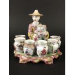 CHINESE FAMILLE ROSE FIGURE OR CENSER modelled as a vase seller seated holding a vase and surrounded