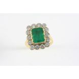 AN EMERALD AND DIAMOND CLUSTER RING the rectangular-shaped emerald is set within a surround of