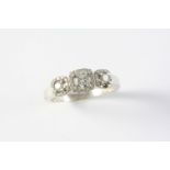 A DIAMOND TRIPLE CLUSTER RING the three graduated circular-cut diamonds are each set within a