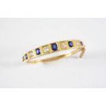 AN EARLY 20TH CENTURY SAPPHIRE AND DIAMOND HALF HINGED BANGLE set to one side with oval-shaped
