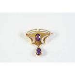 AN ART NOUVEAU AMETHYST AND GOLD BROOCH the gold openwork mount is centred with an oval-shaped