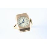 A GOLD WATCH mounted as a ring, the circular white enamel dial with Arabic numerals, 2cm x 1.5cm.