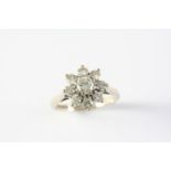 A DIAMOND CLUSTER RING of flowerhead design, the central brilliant-cut diamond is set within a