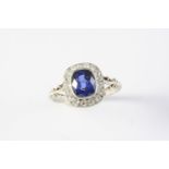 A SAPPHIRE AND DIAMOND CLUSTER RING the cushion-shaped sapphire weighs approximately 2.20 carats and