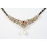 A DIAMOND AND RUBY NECKLACE the oval-shaped ruby is set within a scolling foliate surround of