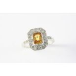 A YELLOW SAPPHIRE AND DIAMOND CLUSTER RING the cut-cornered rectangular-shaped yellow sapphire is