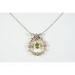 A BELLE EPOQUE PERIDOT AND DIAMOND PENDANT the pear-shaped peridot drop is suspended within a