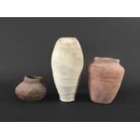 ANTIQUITIES: Three Egyptian pottery vessels, one in buff coloured clay of slender ovoid form,