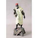 SPELTER FIGURE OF AN ARAB MERCHANT standing wear a fez and white pathani on a stand covered with a