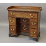 GEORGE III OAK KNEEHOLE DESK with a gallery top above seven drawers, height 85cm, width 92cm,