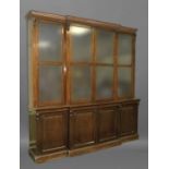 VICTORIAN OAK BREAKFRONT LIBRARY BOOKCASE with four glazed doors an a base with four panelled doors,