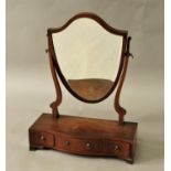 GEORGE III MAHOGANY TOILET MIRROR the shield shaped plate on a serpentine base with three drawers,