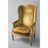 LOUIS XVI STYLE WINGBACK ARMCHAIR the painted and gilt frame upholstered in a gold upholstery, on