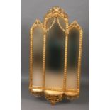 GILTWOOD TRIPLE MIRROR the arched plates beneath a foliate crest and above a shelf, height 150cm,