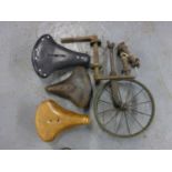 Three Good Saddles, each with leather tops and ready for use. Also, a pair of Vélocipède pedals,