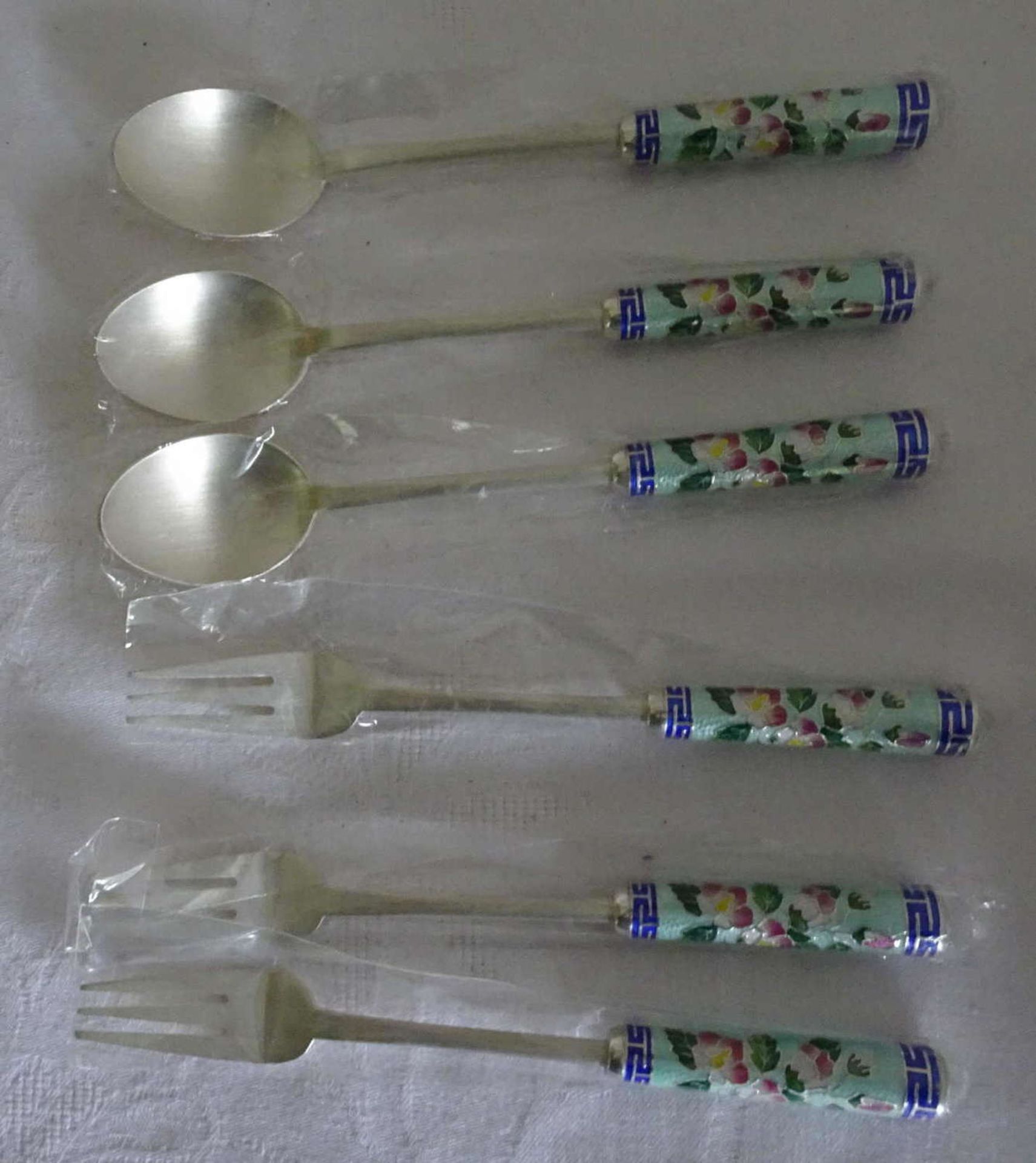 3 cake forks and 3 coffee spoons with enamel handles. Hallmarked 700 + 990. New and unused.