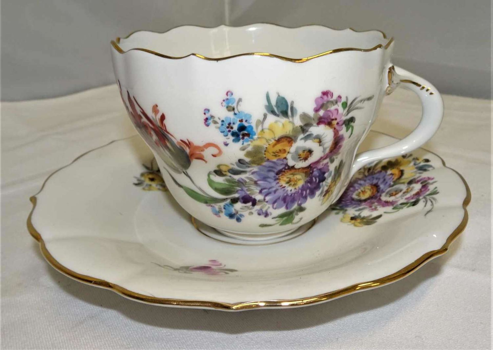 Meissen, 1 Tasse mit Unterteller. Beide gemarkt mit Schwertermarke und 4 Schleifstrichen. Mit