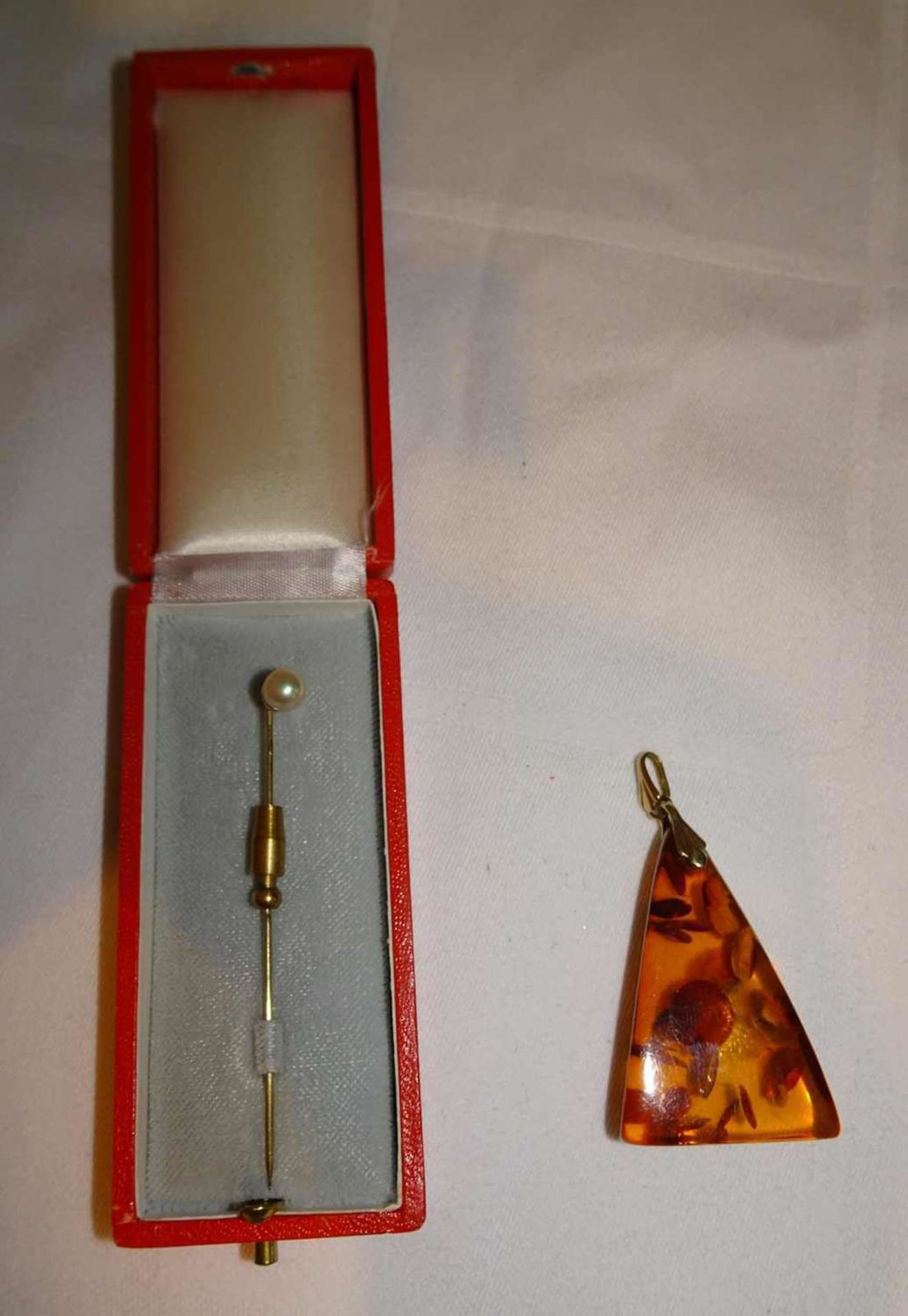 Nadel, 333er Gelbgold besetzt mit 1 Perle. Länge ca. 6,2 cm. Gewicht ca. 1,7 gr., sowie 1 Bernstein