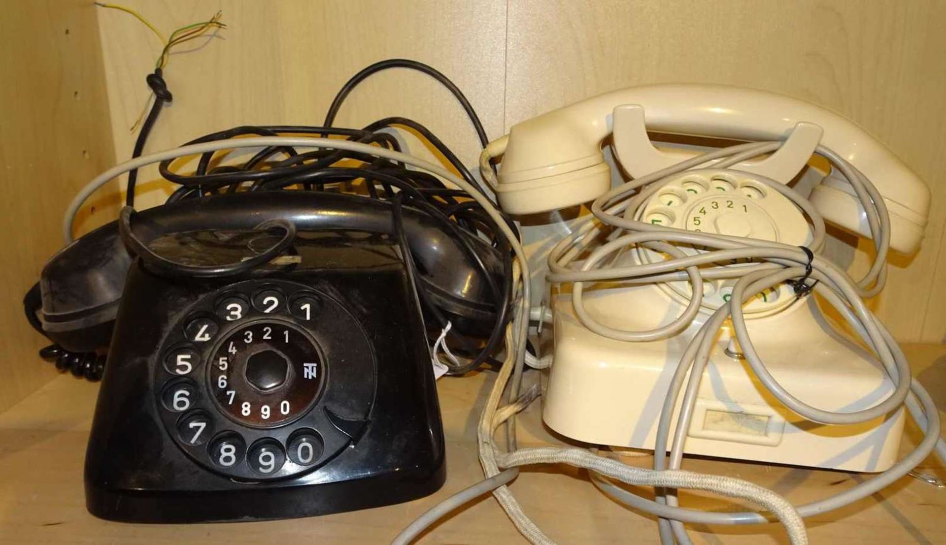 2 ältere Telefone, 1x schwarz, 1x elfenbeinfarben. 2 older telephones, 1x black, 1x ivory.