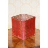 A waste paper bin fashioned from two red and gilt leather books - Cooks Voyages Volumes I & II, with