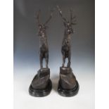 A pair of bronze stags after Jules Moigniez, modelled standing on rocky outcrops, on shaped oval