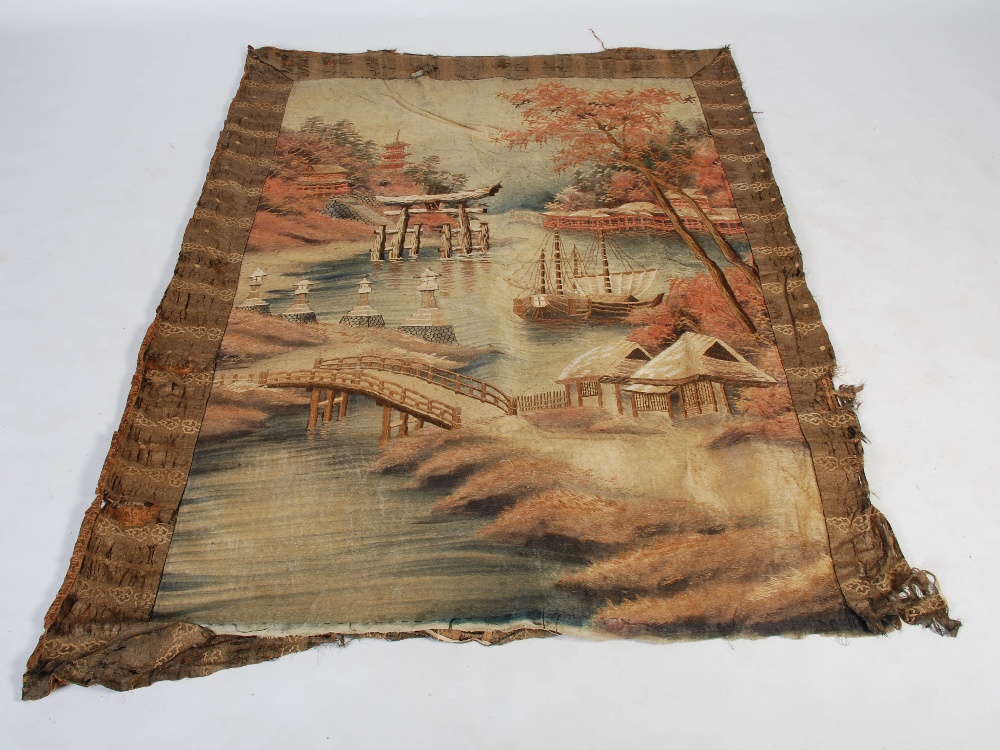 A Japanese silkwork hanging, Meiji Period, worked in coloured threads with river scene, bridge,