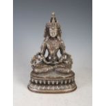 A Tibetan white metal Buddha, seated cross legged on lotus throne, 22cm high x 15cm wide.