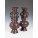 A pair of Japanese bronze twin handled bottle shaped vases, late 19th/early 20th century, cast in