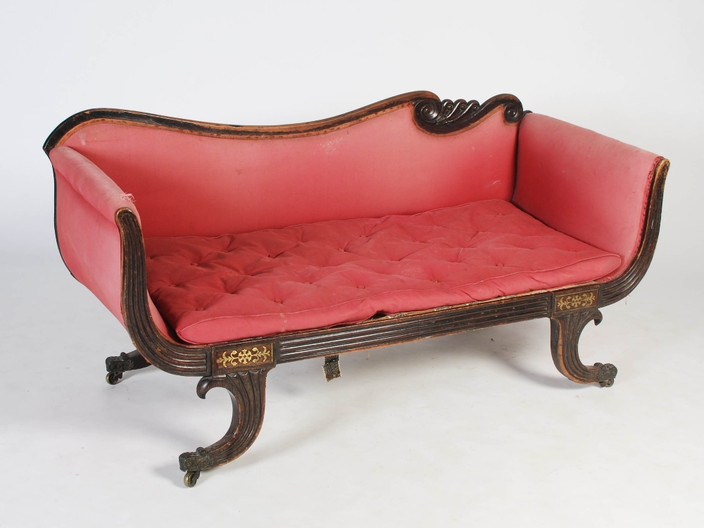 A Regency mahogany and brass inlaid sofa, the scroll carved top rail above an upholstered back and