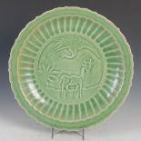 A Chinese porcelain Ming style celadon dish, decorated in relief with crane and stag in fluted