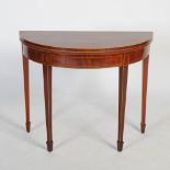 A George III mahogany and boxwood lined demi lune card table, the hinged top opening to a green