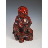 A Chinese carved wood and red lacquered figure of a boy holding sceptre, Qing Dynasty, 28cm high.