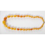 A butterscotch amber necklace, formed as a graduated row of thirty three oval shaped amber beads,