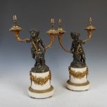 A pair of late 19th century bronze and marble two light candelabra, cast with satyr and cherub