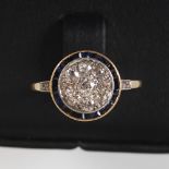 An Art Deco yellow and white metal sapphire and diamond cluster ring, centred with a round brilliant