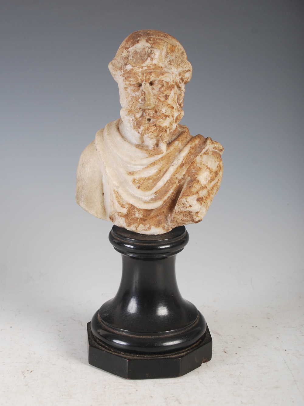 Antiquities- An antique Roman marble bust of a bearded male, mounted on weighted ebonised socle