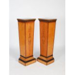 A pair of late 19th century satinwood, ebonised and marquetry inlaid pedestals, the rectangular tops