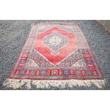 A Persian rug, 20th century, the madder ground centred with a large lozenge shaped medallion, within