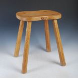 Mouseman - a carved oak cow stool, the shaped top with an adzed finish raised on four tapered