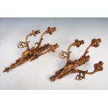 A pair of gilt metal three light wall sconces in the Neoclassical taste, cast with arrows, cherubs