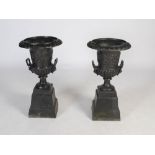 A pair of late 19th/early 20th century twin handled cast iron garden urns, of Campagna form, cast in