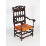 A late 19th century carved oak armchair, the rectangular back with pierced and foliate carved top